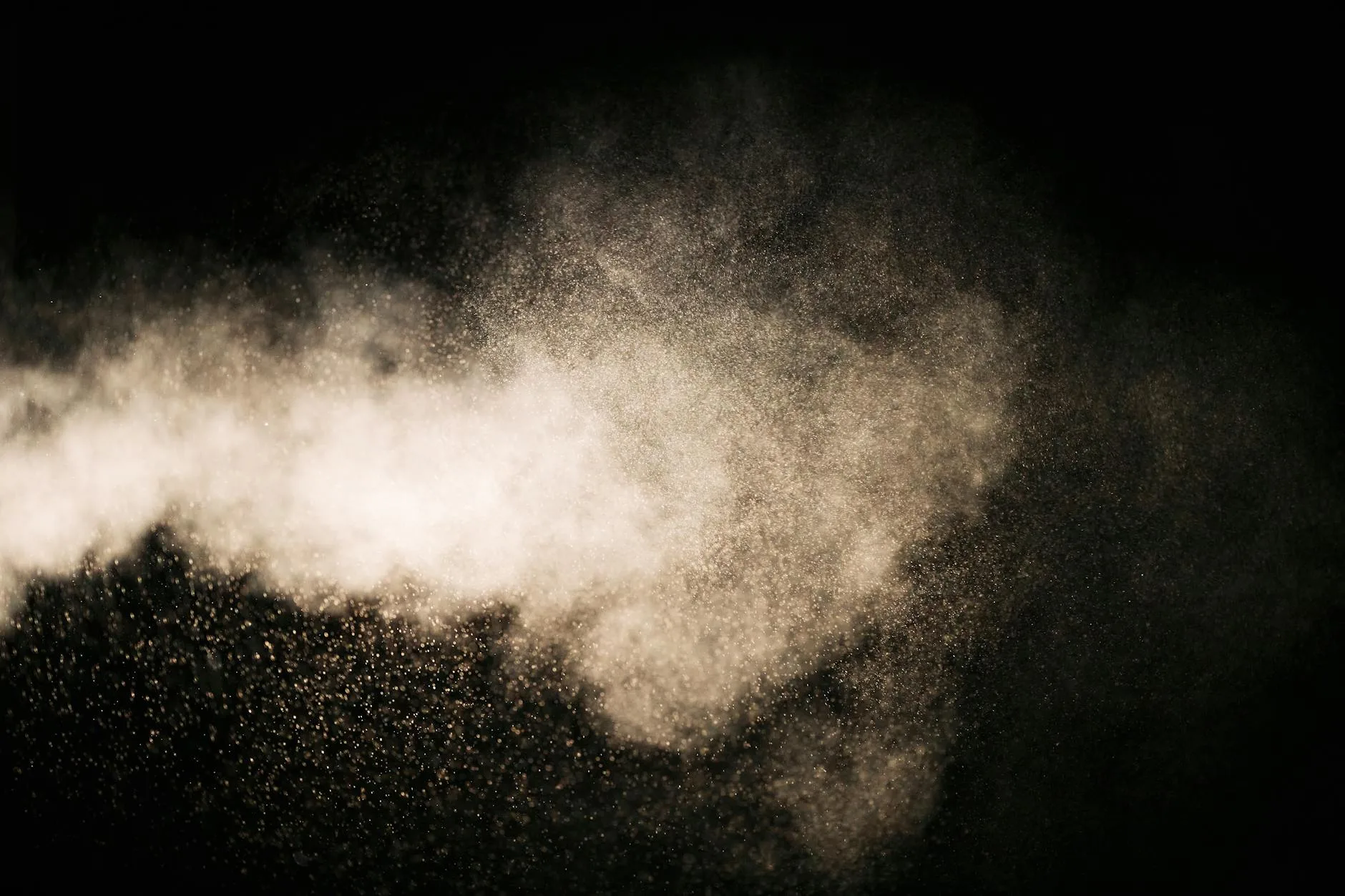 Close-up of airborne dust particles against a dark background